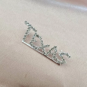 Macro shot of Texas word brooch with sparkling rhinestones on champagne silk fabric