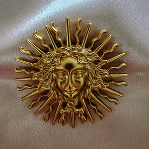 Detailed macro view of vintage sun goddess golden brooch on soft fabric background