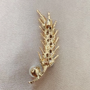 Golden wheat stalk brooch with rhinestones and pearl on champagne satin background