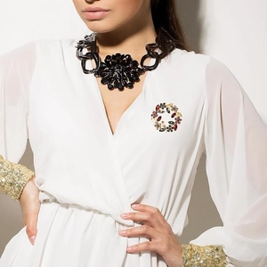 Detailed close-up of a floral crystal brooch on a model's white V-neck blouse