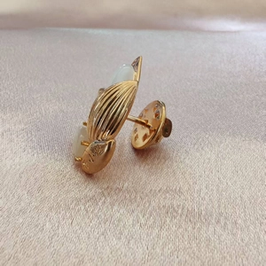 Détail de la broche dorée en cuivre avec feuille d'opale et logo gravé