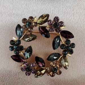Golden wreath brooch featuring multicolor marquise crystals on a rose gold silk background
