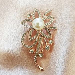 Elegante roségouden bloemspeld met fonkelende steentjes en een grote centrale parel