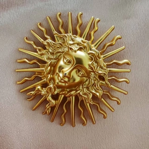 Detailed close-up of golden sun goddess brooch with intricate rays and face relief