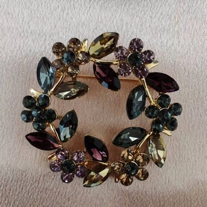 Detailed macro of crystal floral wreath brooch with colorful rhinestones on golden base