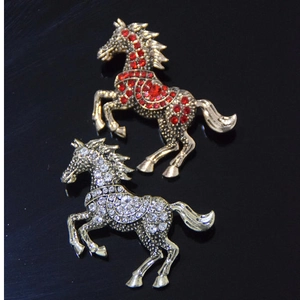 Close-up of sparkling horse brooches with red and white rhinestones on gold base