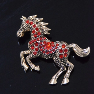 Detailed macro view of vintage gold horse brooch with sparkling red rhinestone accents