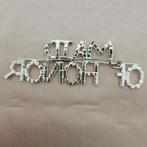 Detailed back view of the silver letter brooch showing secure safety pin and welding