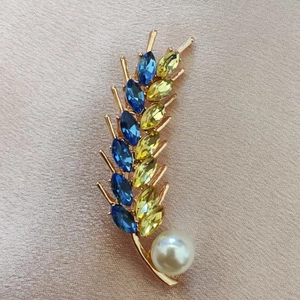 Macro view of crystal wheat brooch with blue and yellow stones and a white pearl