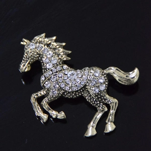 Elegant gold-tone running horse brooch with sparkling crystals on a black background