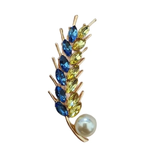 Elegant rose gold wheat brooch with blue and yellow crystals and a white pearl accent