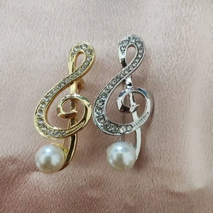 Detail view of musical note brooch with sparkling rhinestones and a white pearl accent