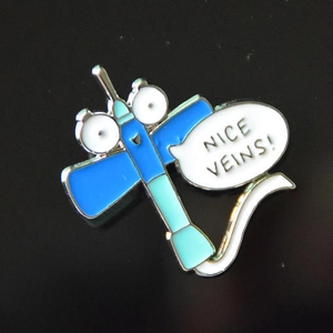 Cartoon-Emaille-Anstecknadel mit blauer Spritze und 'NICE VEINS!'-Schriftzug auf Schwarz