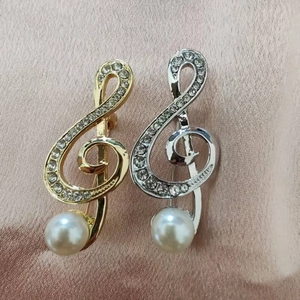 Detail of gold and silver musical note brooches with crystals and pearls on silk