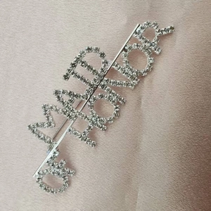 Detailed close-up of silver rhinestone Maid of Honor hair pin on pink silk background