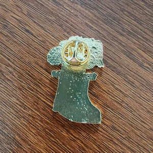 Dettaglio retro spilla in metallo dorato con chiusura a farfalla su legno