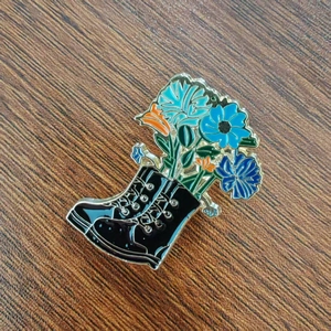 Dettaglio ravvicinato di una spilla creativa in smalto a forma di stivale nero con fiori