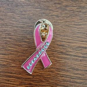 Close-up of pink enamel ribbon brooch with gold metal base and blue rhinestones