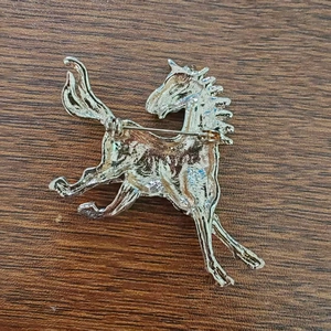 Vista posteriore di una spilla a forma di cavallo dorata con chiusura a spillo