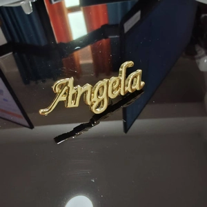 Dettaglio macro di spilla personalizzata placcata oro 3D con scritta Angela