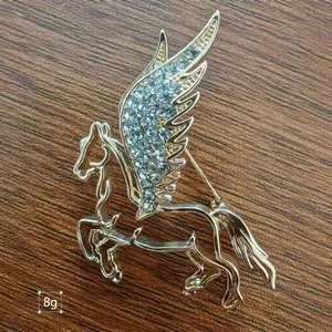 Elegant gold Pegasus brooch with light blue rhinestones on a rustic wooden background