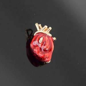 Detail of anatomical heart brooch with red enamel glaze and gold metal vascular accents