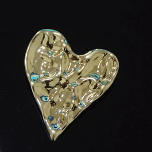 Vue macro d'une broche de luxe en forme de cœur dorée avec texture métallique martelée