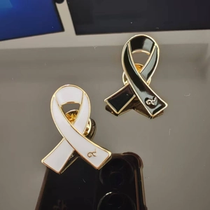 Macro view of black and white enamel ribbon brooch pins with gold alloy plating