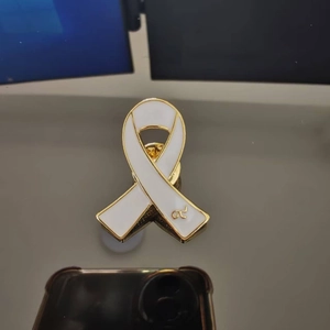 Detailed macro view of white enamel ribbon brooch with golden Thai number nine character