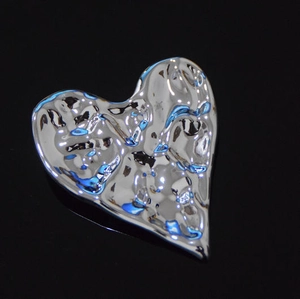 Détail de la broche cœur argentée avec texture martelée et fini métallique poli