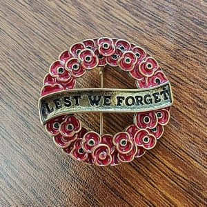 Lest We Forget poppy wreath brooch with red enamel and metal ribbon engraving