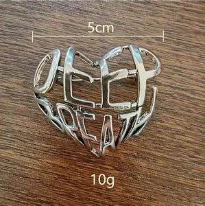 Broche cœur évidée argentée avec lettres et finition métallique sur surface en bois