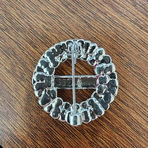 Silver circular wreath brooch with red poppy floral detail and secure pin clasp