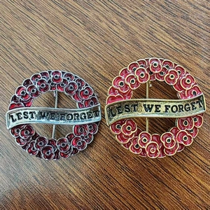 Detailed macro view of enamel poppy remembrance brooches with Lest We Forget engraving