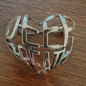 Broche en forme de cœur argenté ajouré avec lettrage Deep Great sur fond en bois