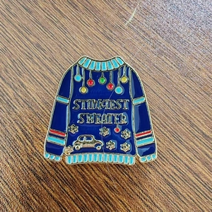 Detail of blue enamel Christmas ugly sweater brooch with colorful ornaments and gold trim