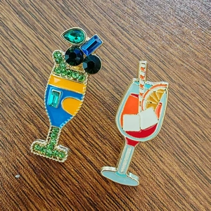Detailed macro view of cocktail enamel brooches with crystal inlay on dark wood background