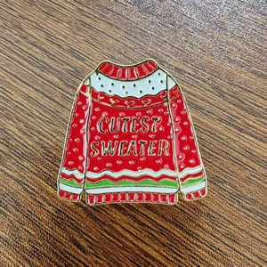 Detail of red Christmas sweater enamel brooch with Cutest Sweater text engraving