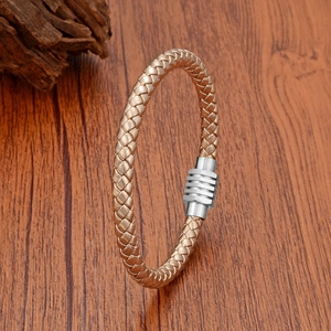 Close-up of golden braided leather bracelet with silver magnetic metal clasp on wood
