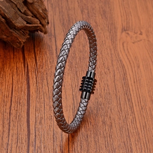 Detail of woven leather bracelet with black magnetic clasp on rustic wood background