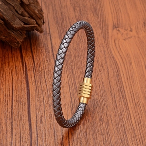 Braided leather bracelet with geometric gold magnetic clasp on a natural wooden surface