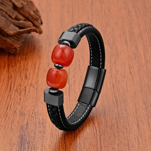 Men's woven black leather bracelet with red beads and magnetic clasp on wooden surface