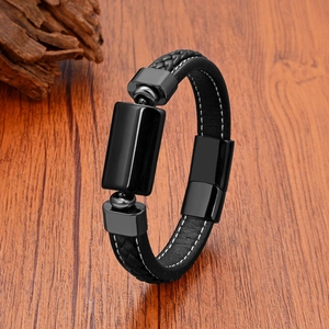 Detailansicht eines Herrenarmbands aus schwarzem Leder mit Flechtmuster und Metallelement