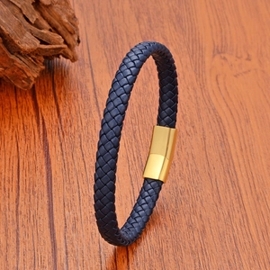 Détail d'un bracelet en cuir tressé bleu avec fermoir magnétique doré sur fond bois