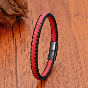Détail du bracelet en cuir tressé rouge et noir avec fermoir magnétique noir sur bois
