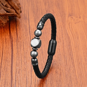 Detail of woven black leather bracelet with gunmetal beads on a wooden background