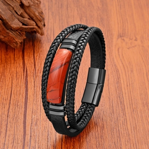 Détail d'un bracelet en cuir tressé multi-rangs avec pierre rouge et fermoir magnétique