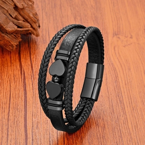Détail du bracelet en cuir tressé multicouche avec breloques cœurs noirs et fermoir aimanté