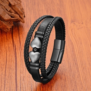 Détail d'un bracelet multicouche en cuir tressé noir avec breloques cœur et fermoir aimanté
