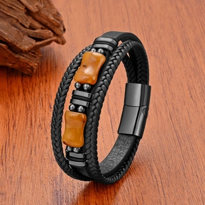 Vue macro du bracelet en cuir tressé multicouche avec pierres d'ambre et fermoir aimanté